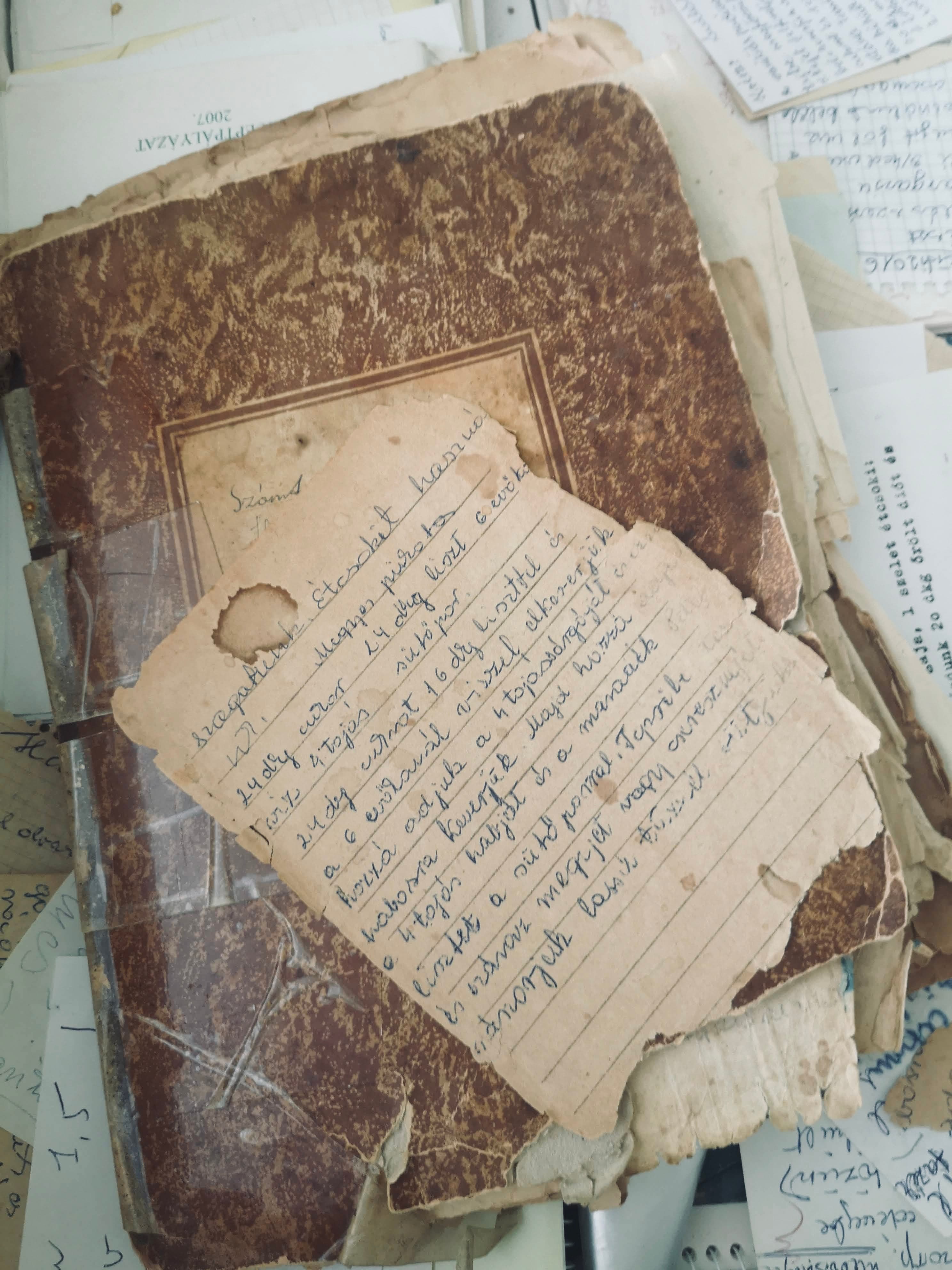 Grandmother's handwritten recipe book, its cover worn and a loose page of the diócska recipe on top
